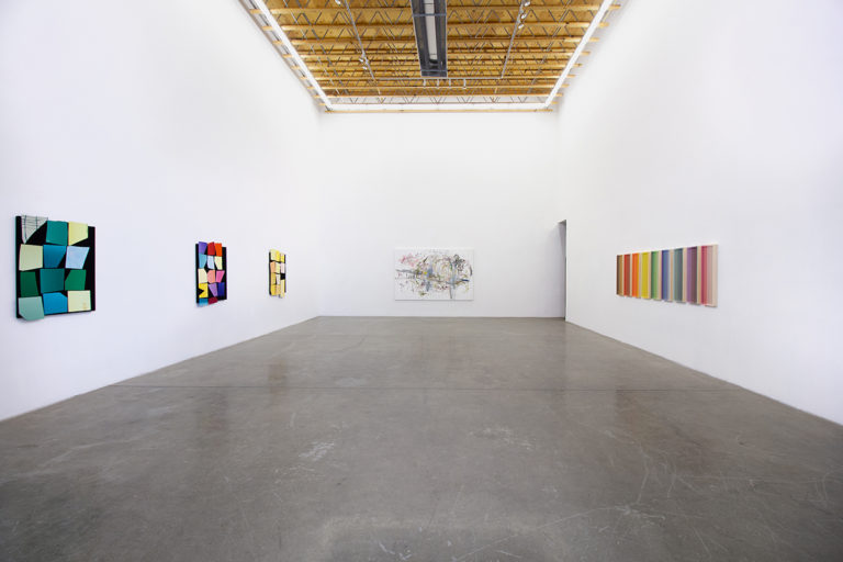 Installation image of An Imprint of the Smallest Gesture that shows three similar works that features a black panel that has yellow, green and multi colors of bright and vivid papers papers collage on the surface, an abstract painting that consists of bright and vivid, and earth-tone paints and a wall installation that consists of nine panels that are painted of bright and vivid colors