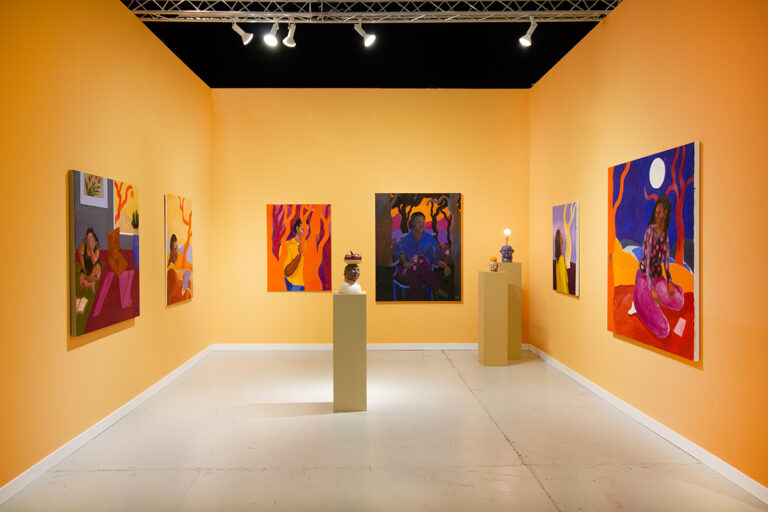 Various paintings and sculptures installed in a yellow room.