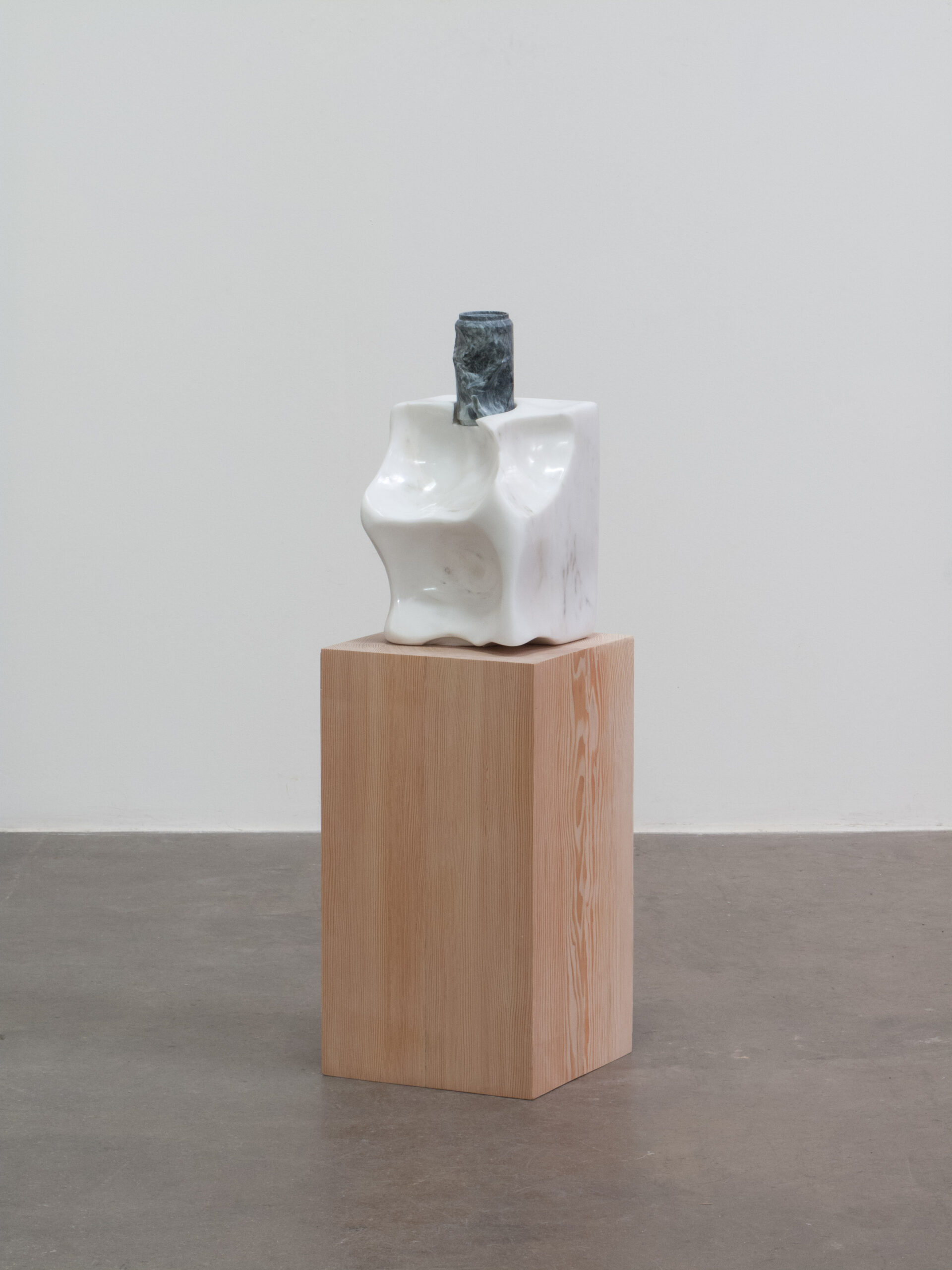 A carved marble sculpture resembling a salt lick and a carved soapstone beer can sit atop a wood pedestal.