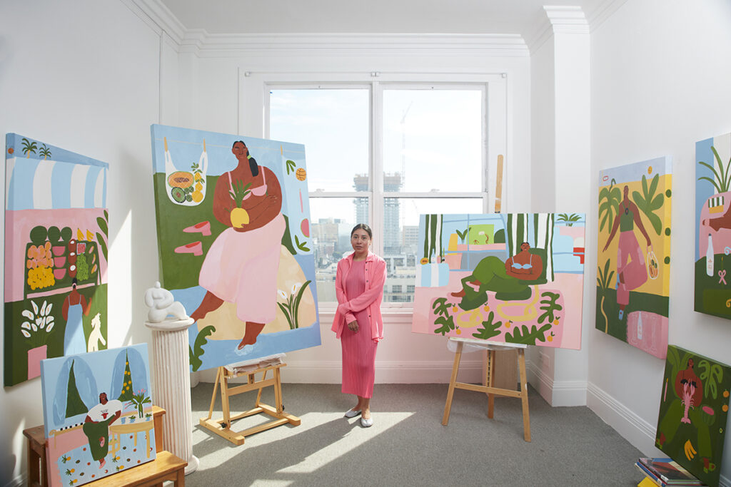Artist Lilian Martinez in her DTLA studio surrounded by her paintings in a sunlit room